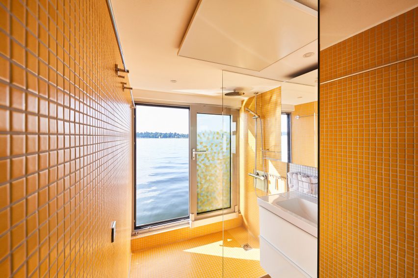 Bathroom by Crossboundaries lined with yellow tiles overlooking water