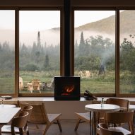 Cafe interior with wooden furniture, gas stove and large windows overlooking a grassy hill