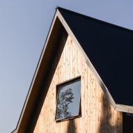 Close-up of the top of a pitched roof with a square window and timber-clad facade