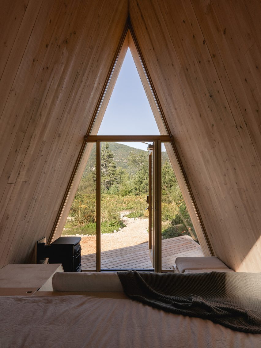 Interior of an A-frame cabin structure with glass door overlooking the landscape