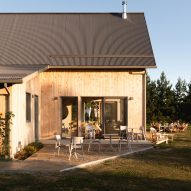Exterior of a barn-style cafe with timber cladding, charcoal steel roof and outdoor seating