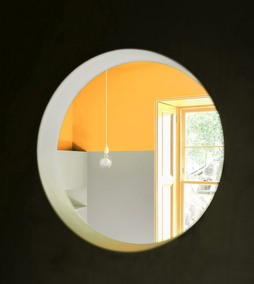 Small circular hole showing view to yellow living area