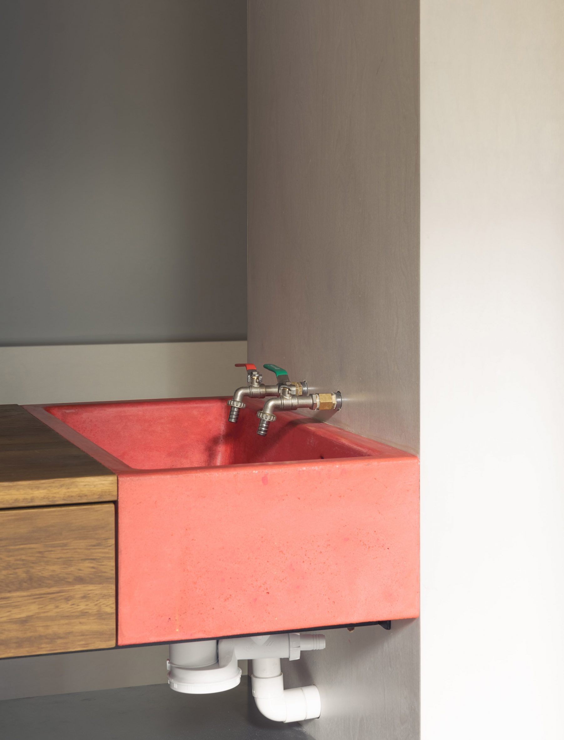 Oversized red cast-concrete sink in kitchen of micro apartment