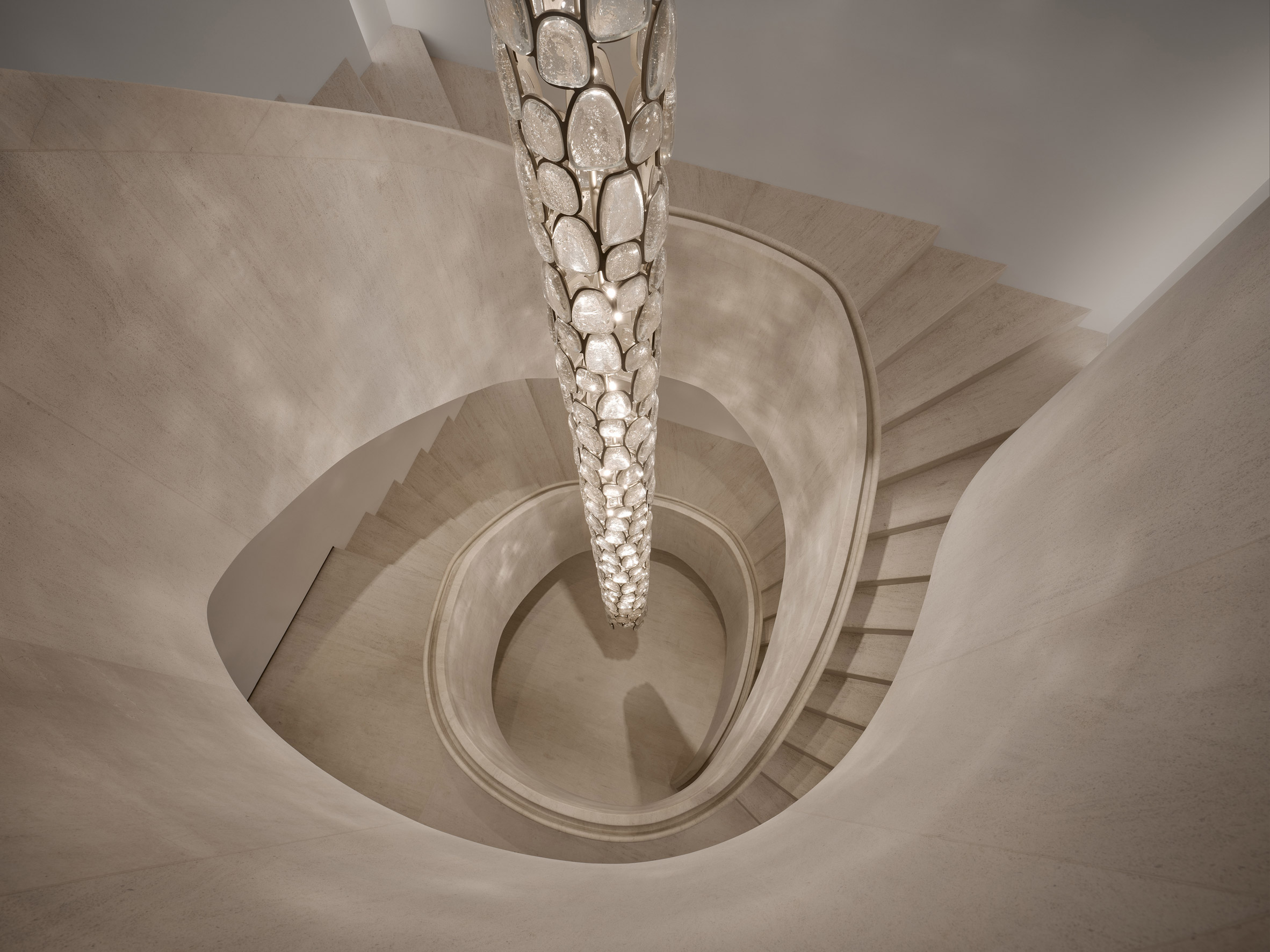 Sinuous limestone staircase surrounds 30-foot glass lighting fixture