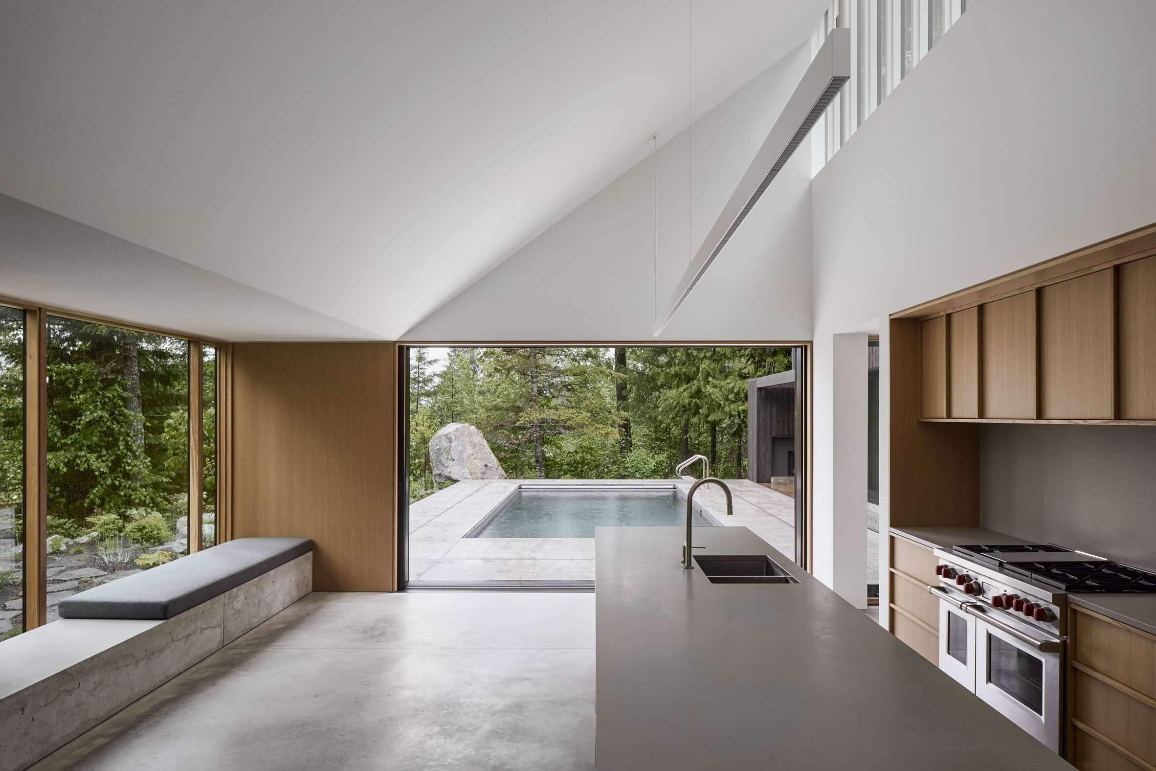 Open-plan kitchen illuminated by skylights, which opens onto a terrace with a long swimming pool