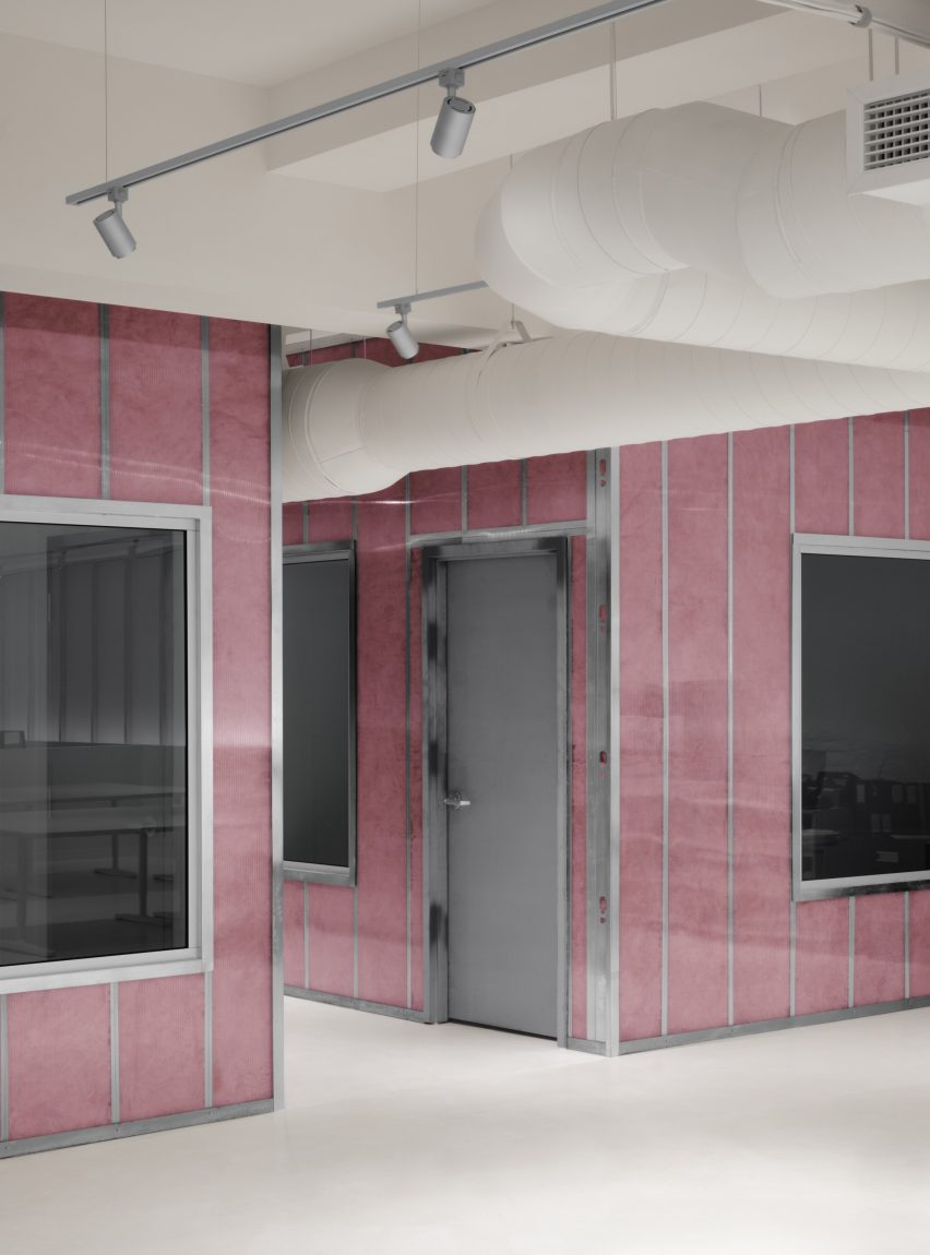 Изоляция из розового стекловолокна, проступающая через стеновые панели из поликарбоната.