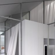 Mono-pitched steel interior with a white box room and white curtains