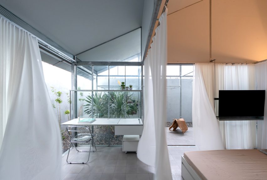 White curtains dividing interior office and living spaces in Binh Thuan House