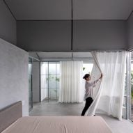A grey bedroom with a white curtain room divider being pulled back
