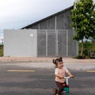 Exterior of a mono-pitched home by MIA Design Studio with a child playing on the street in front