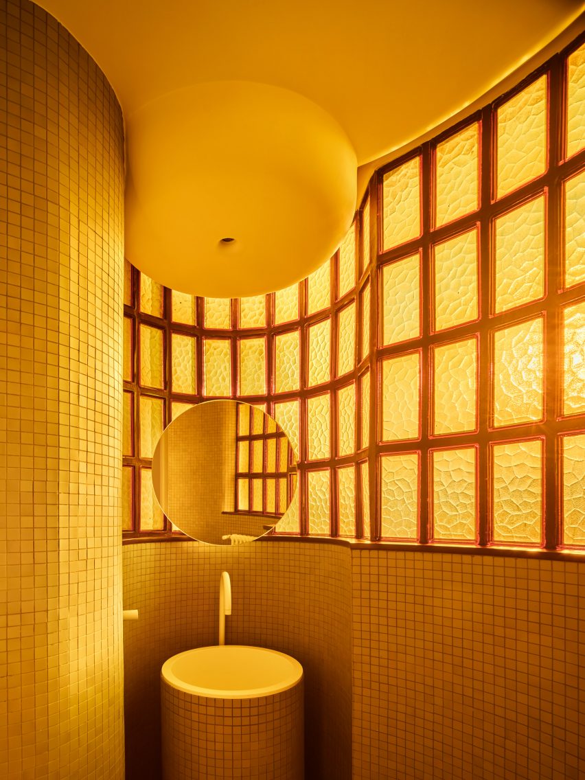 Amber light shining through original windows in apartment bathroom designed by Studio Noju 