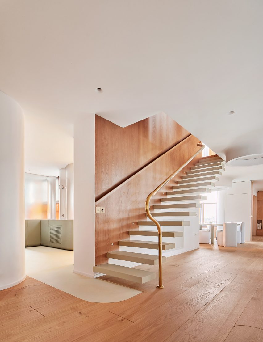 Floating staircase placed against oak panelling in apartment by Studio Noju