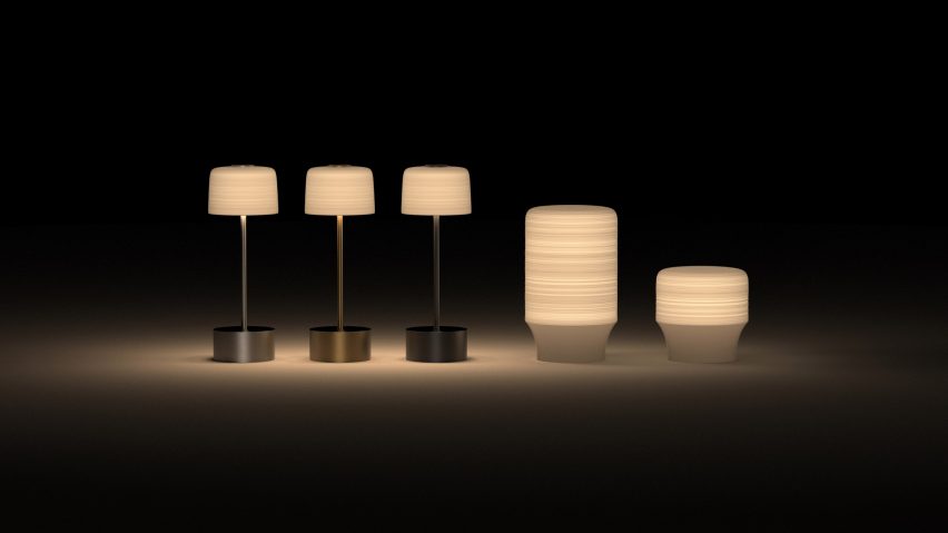 Three taller and two shorter table lamps glowing in front of black backdrop