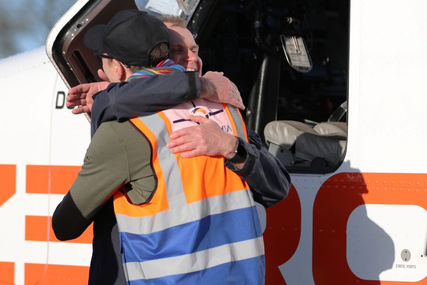 Photo of two men hugging next to a small aircraft