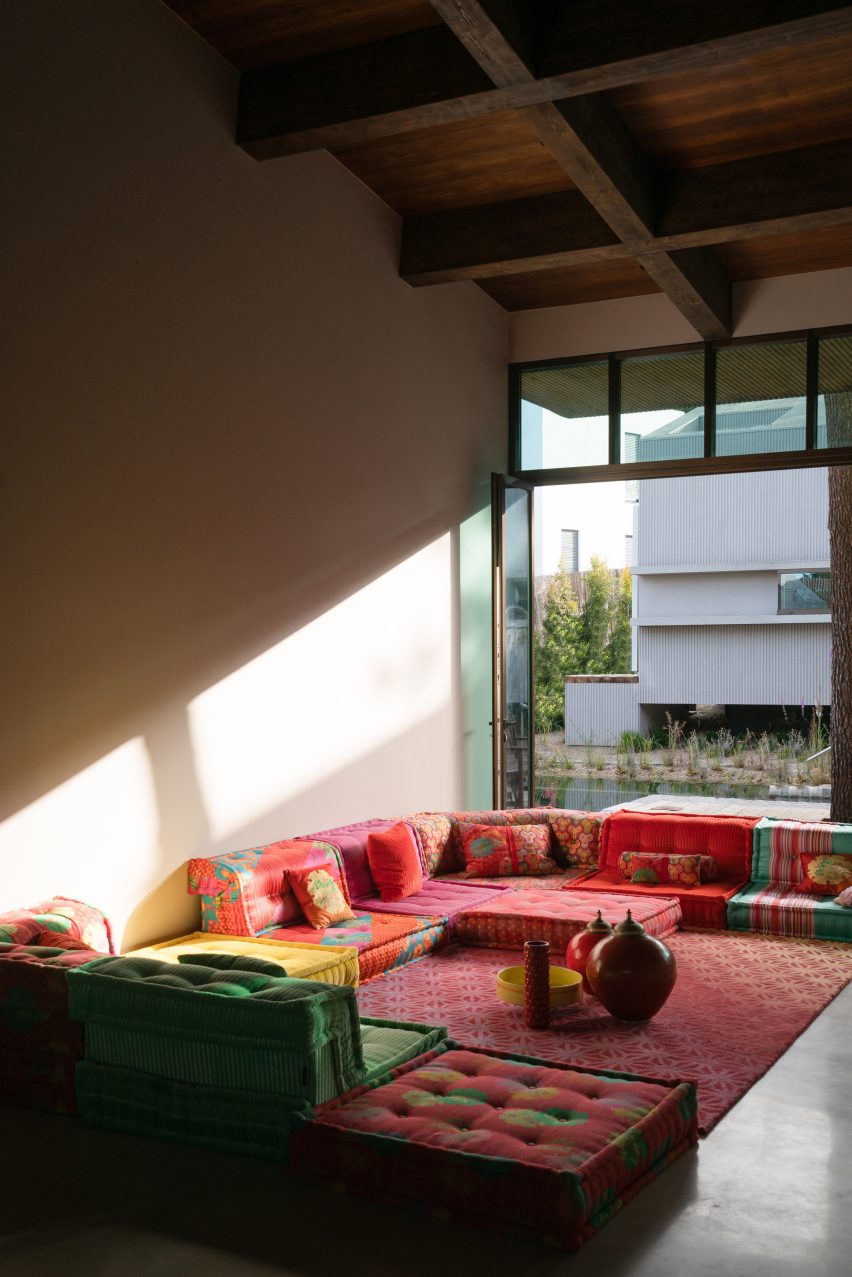 Fotografie obývacího pokoje s dřevěným stropem a barevnými pohovkami