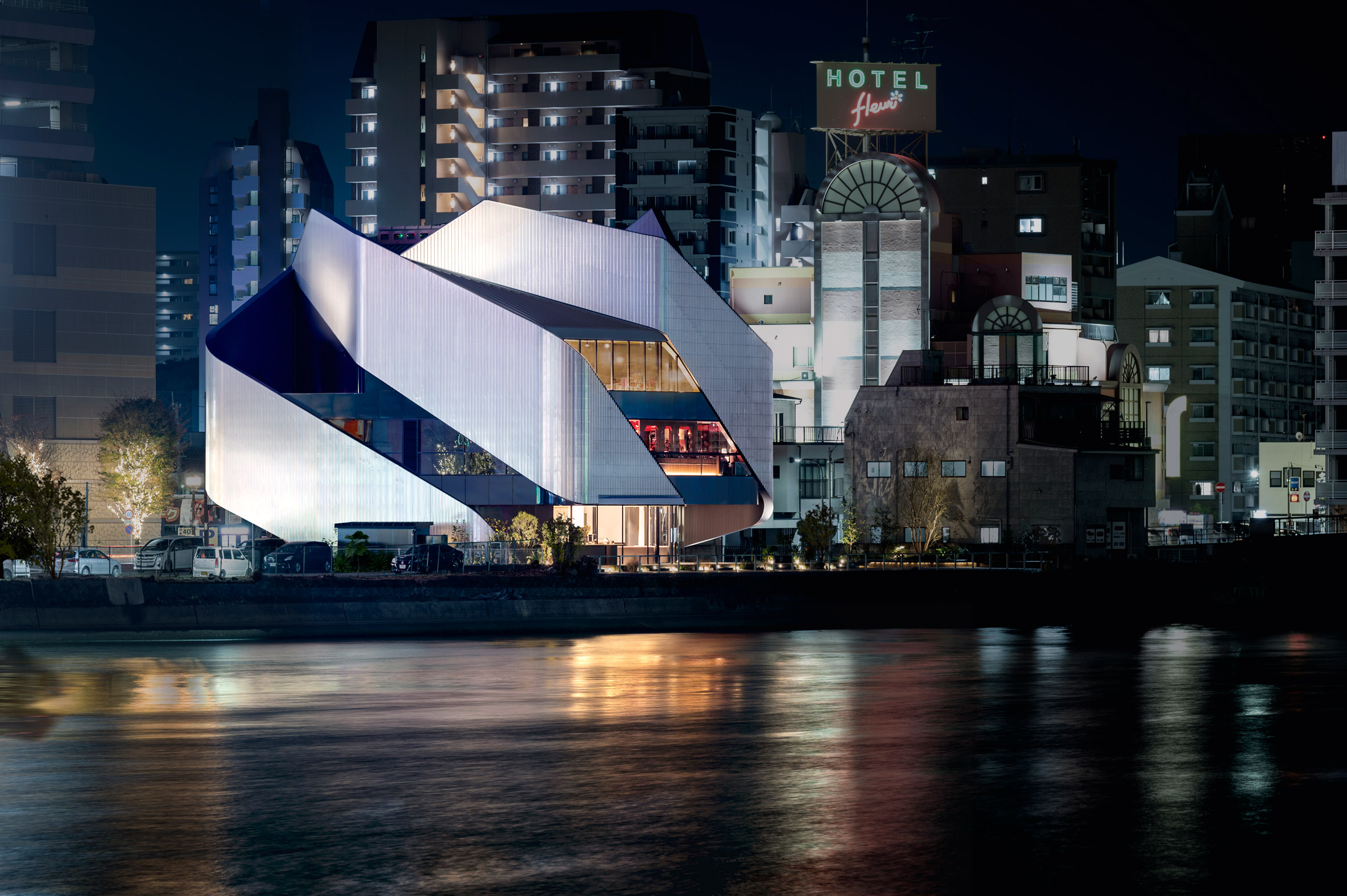 A theatre building on a city waterfront with sweeping steel panels covering the exterior