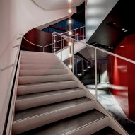 Staircase in an atrium space with suspended lighting at the centre and white and red walls