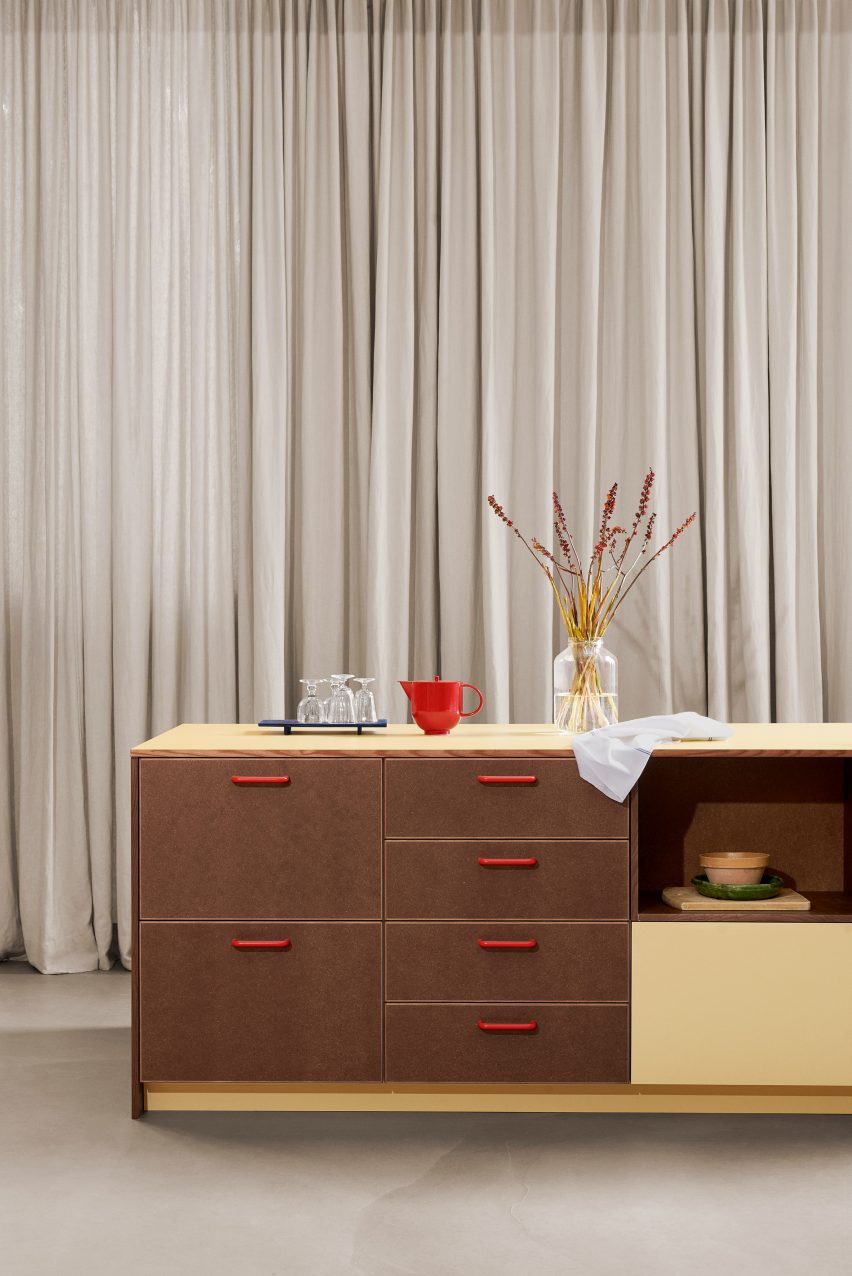 Kitchen island with red handles in front of long curtains