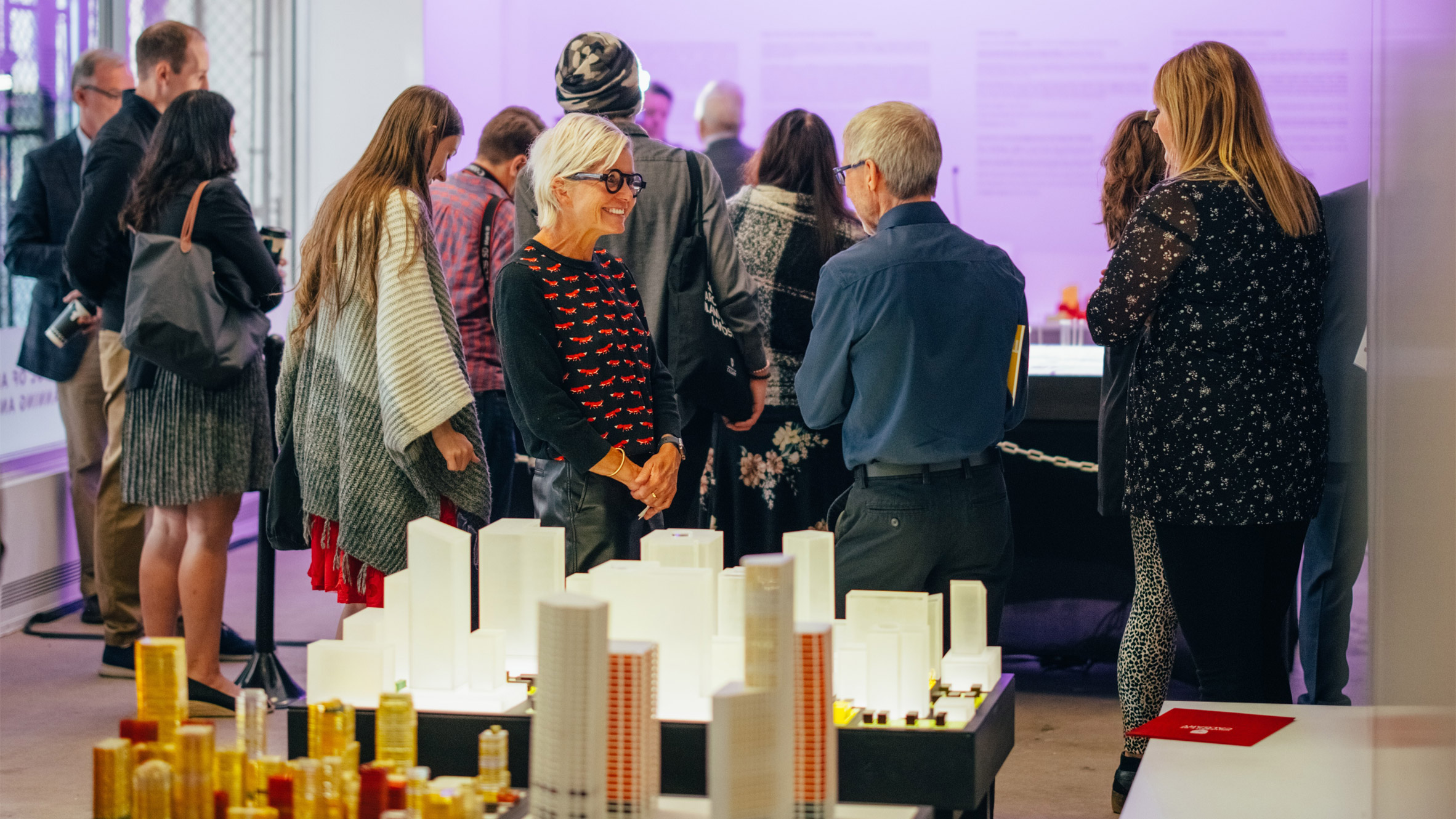 People gathered at a University of Calgary event with tables filled with architecture models