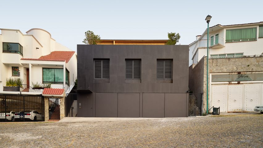 Black rectangular house with black shutters and a wooden roof terrace