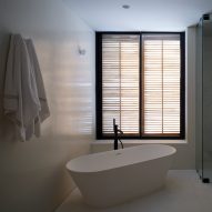 White bathroom with freestanding bathtub and window shutters