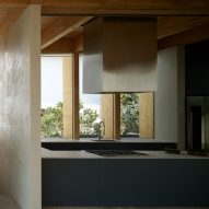 Open-plan kitchen with timber roof structure, silver extractor fan and blue kitchen cabinets