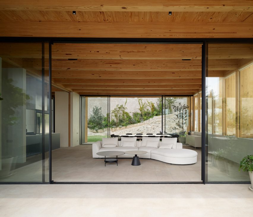 Terrace with large sliding glass doors leading to an open-plan living room with a white sofa and timber roof structure