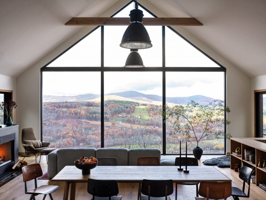 Otevřený prostor jídelny a obývacího pokoje s proskleným štítem s výhledem do kopcovité krajiny