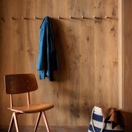 Wood-panelled wall with coat pegs and a wooden chair