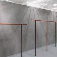 Grey shop interior with curved walls and orange clothes rails and hooks