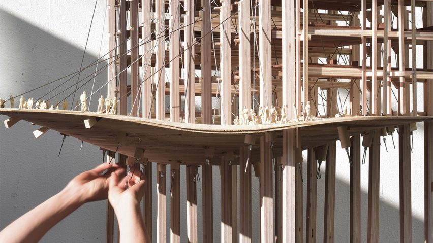 A student's hands touching complex architectural model