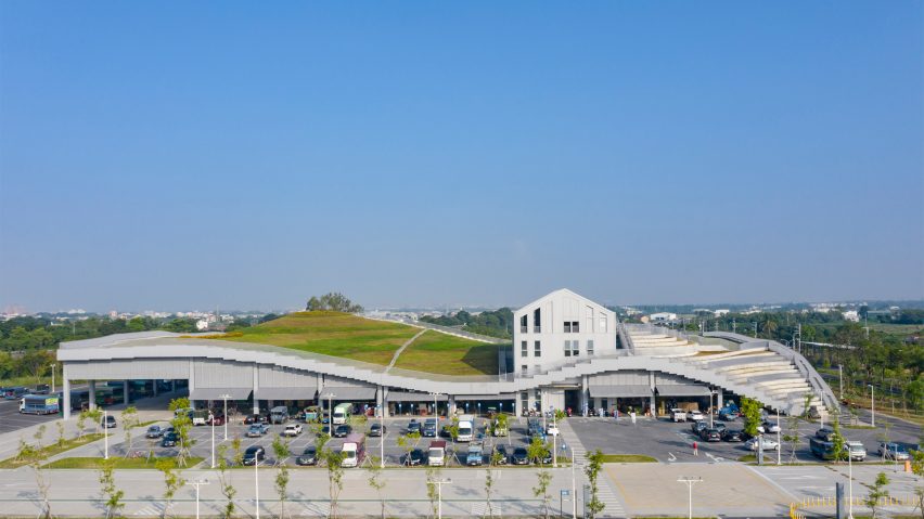 Large market building with a curving grass roof punctuated by a pitched-roof building