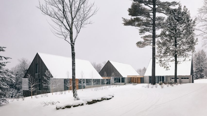 Three cabins with metal gable ends and granite stone walls on a snowy mountainside