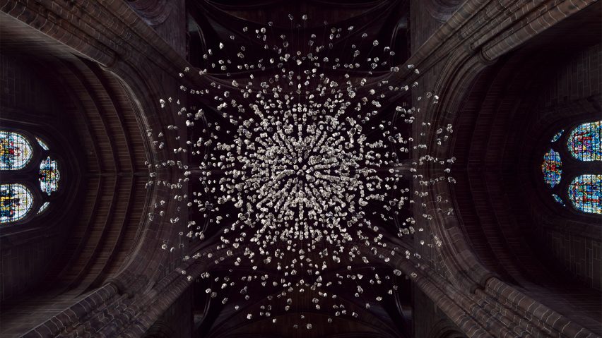 View from below of a spherical installation made up of suspended piece of coal illuminated inside a cathedral