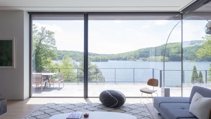 Lounge with corner glazed doors leading to a terrace overlooking a lake