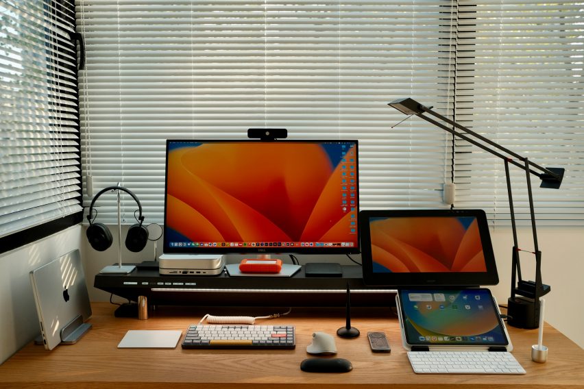 Photo of a home workspace with three screens arranged around the Hexcal Studio desktop management platform, along with accessories like a keyboard and hard drives