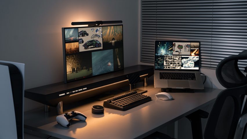 Photo of a desktop with a monitor, laptop and accessories supported on the Hexcal Studio desktop management system, lit by the soft glow of an indirect light