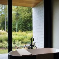 A bathroom with a freestanding bathtub and floor-to-ceiling windows overlooking a planted garden