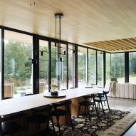 An open-plan living and dining room with a long wooden table and floor-to-ceiling windows