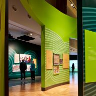 Interior museum gallery space with wood flooring and green wall partition displays