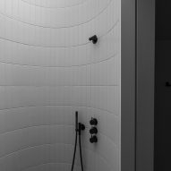 Circular white-tiled shower with a skylight and black fixtures