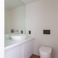 White bathroom with counter-top sink, toilet and brick floor