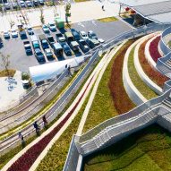 A series of stepped terraces filled with different coloured planting leading to a car park
