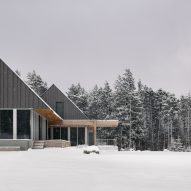 Two cabins with granite walls and metal-clad gable ends in a snowy forest