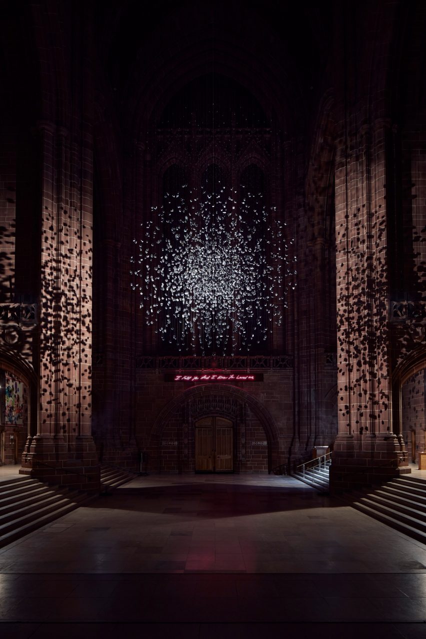 Spherical installation made up of suspended piece of coal illuminated inside a cathedral with a Tracey Emin neon light