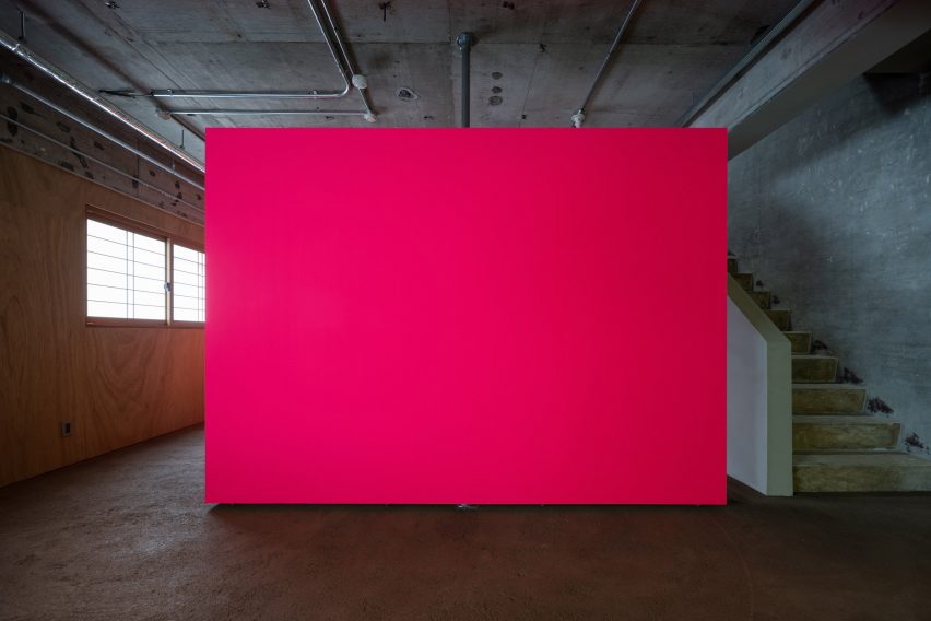 Pink fluorescent partition wall in an industrial apartment with concrete staircase to the side