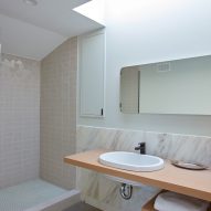 Bathroom with walk-in shower, white basin on a wood worktop and cream marble splashback