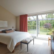 Bedroom with a double bed, ottoman, timber floors and double glass sliding doors that open to a garden