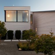Two-storey cedar-clad home with large windows and gravel front garden with trees