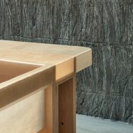 Corner of a translucent tabletop with a timber frame in a room with textured stone walls